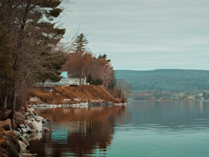 a body of water with a house on a hill in the background