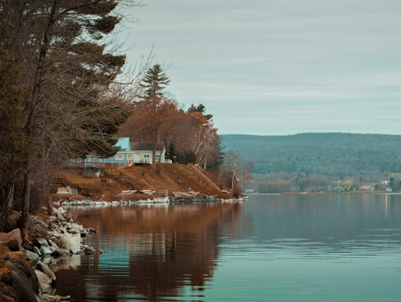a body of water with a house on a hill in the background