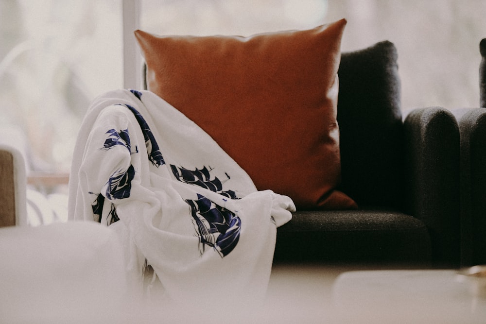 a white blanket sitting on top of a couch next to a window