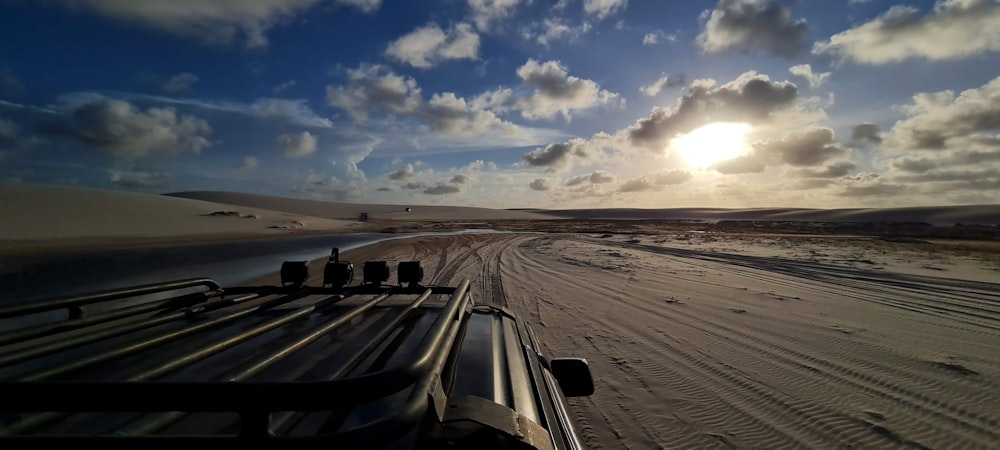 a truck driving down a desert road under a cloudy sky