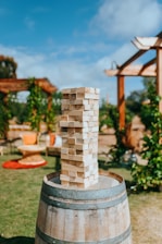 A lively family playing giant Jenga in a sunny backyard.