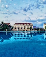 a large swimming pool with a hotel in the background