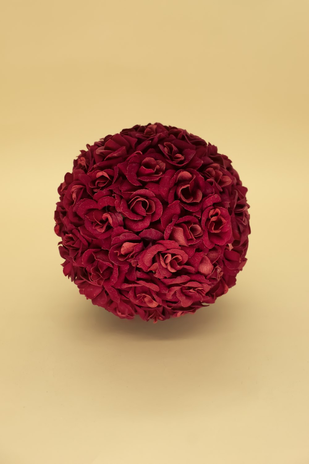 uma bola de flores vermelhas sentada em cima de uma mesa