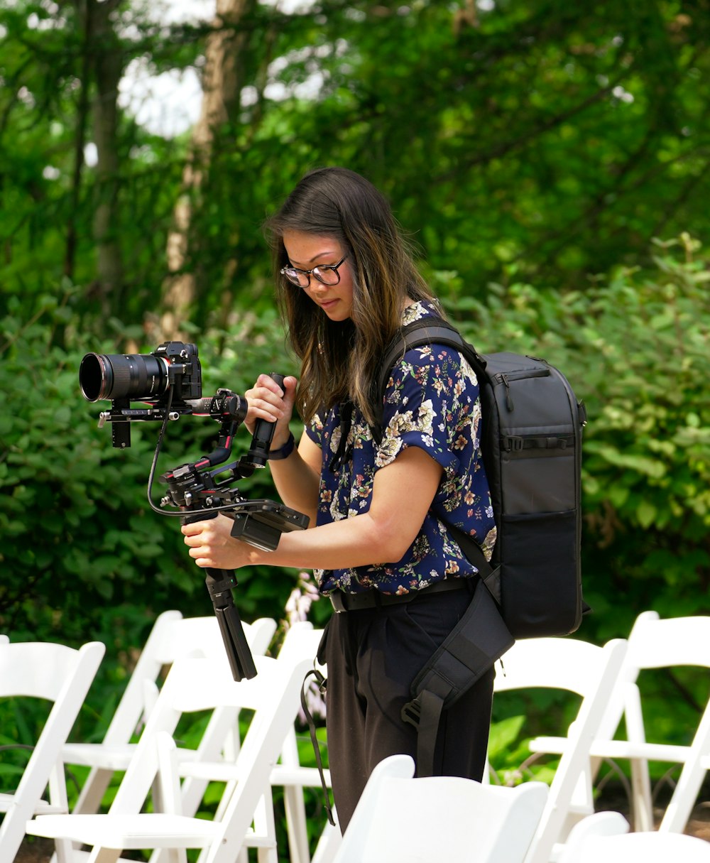 a woman standing in front of white chairs holding a camera