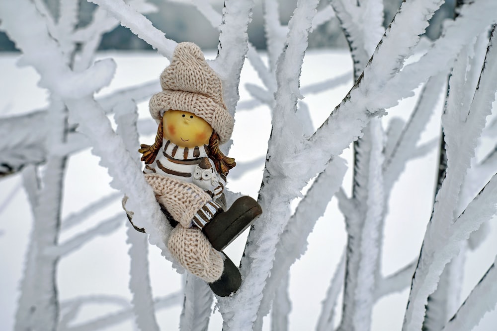 a stuffed animal sitting on top of a snow covered tree