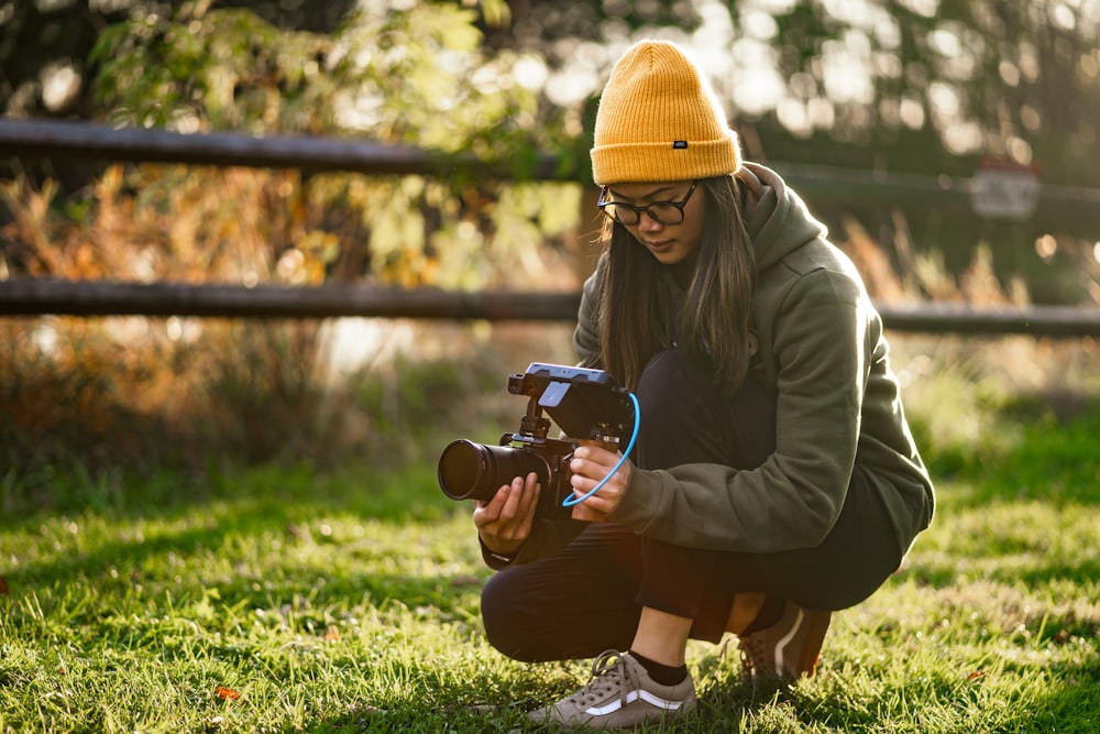 a woman kneeling down while holding a camera