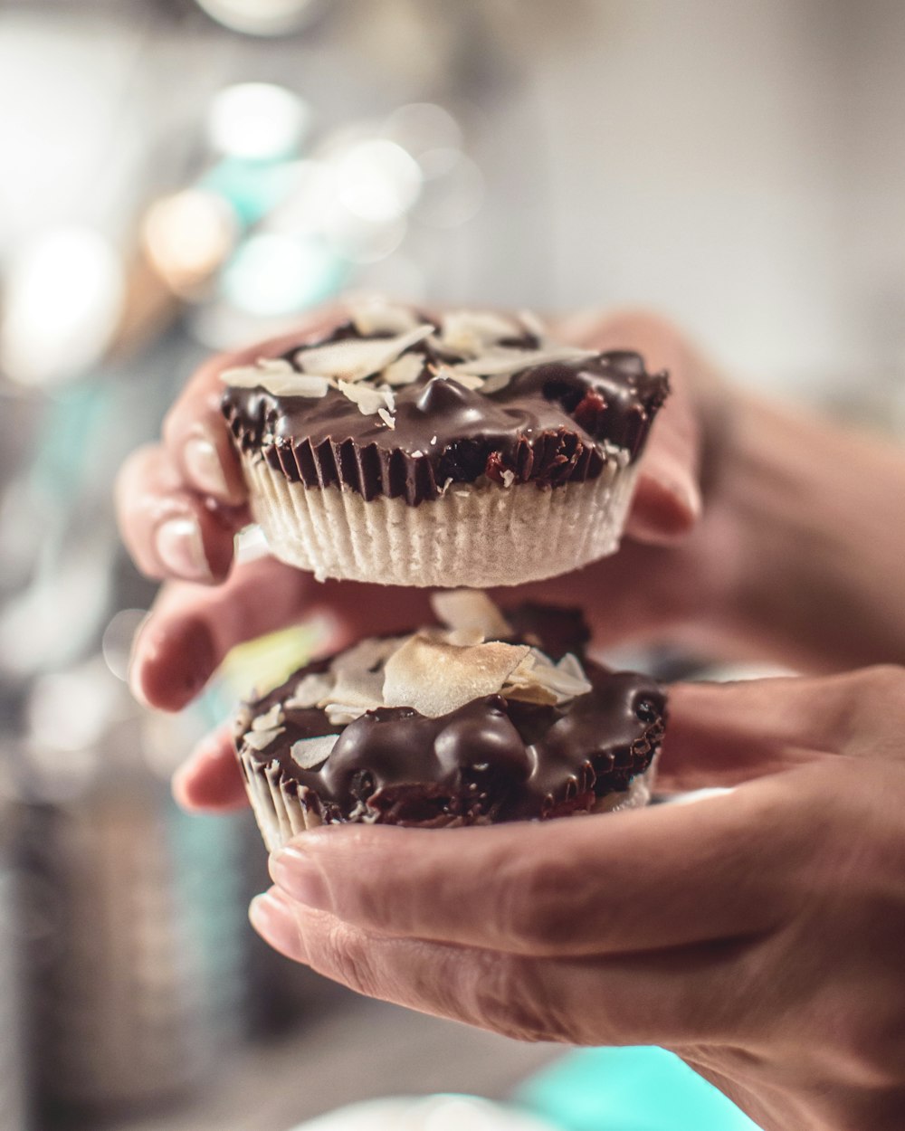 a close up of a person holding two cupcakes