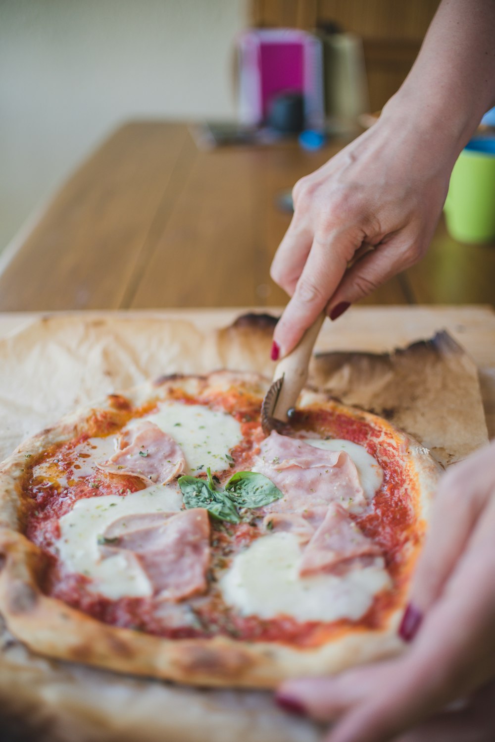 a person cutting a pizza with a pizza cutter