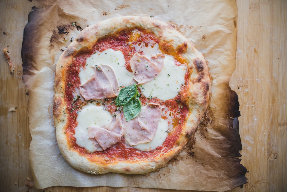 une pizza avec de la viande et du fromage sur un morceau de papier ciré