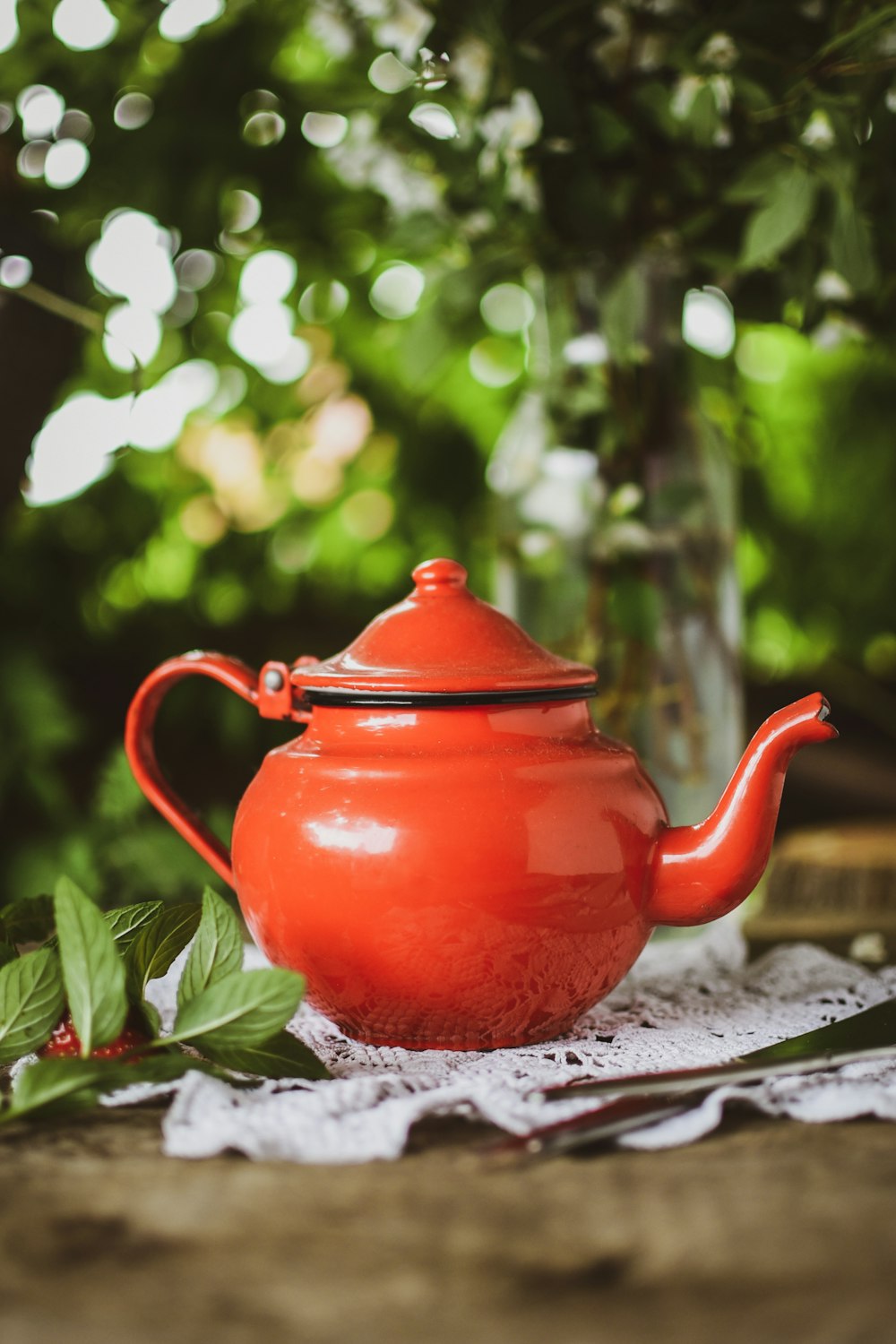 um bule de chá vermelho sentado em cima de uma mesa