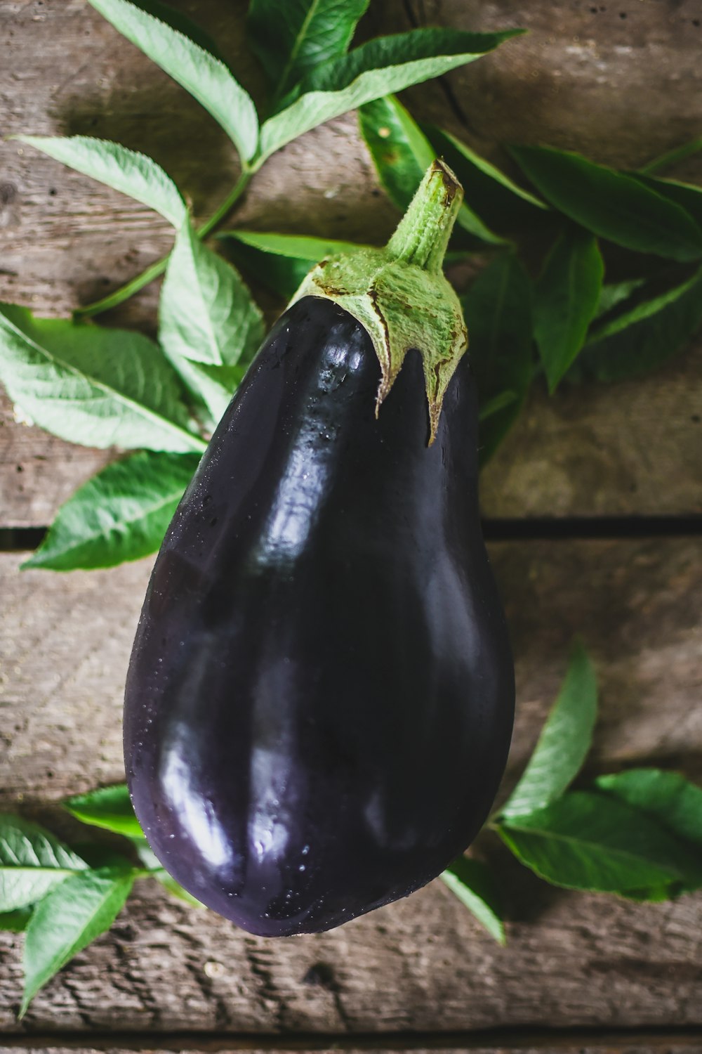 une aubergine sur une surface en bois avec des feuilles