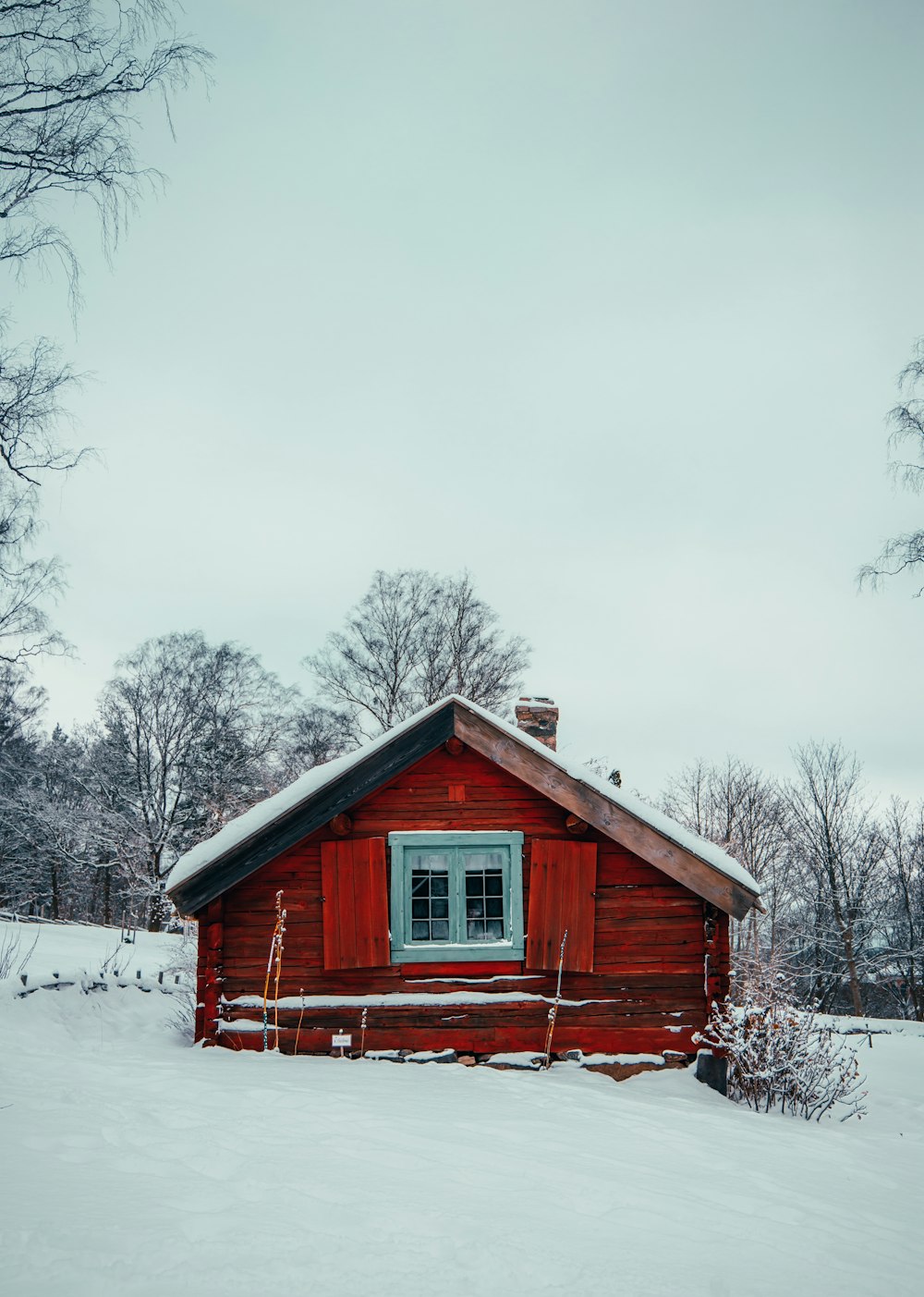 a red cabin in the middle of a snowy field