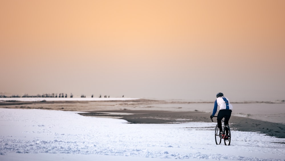 a person riding a bike on a snowy beach