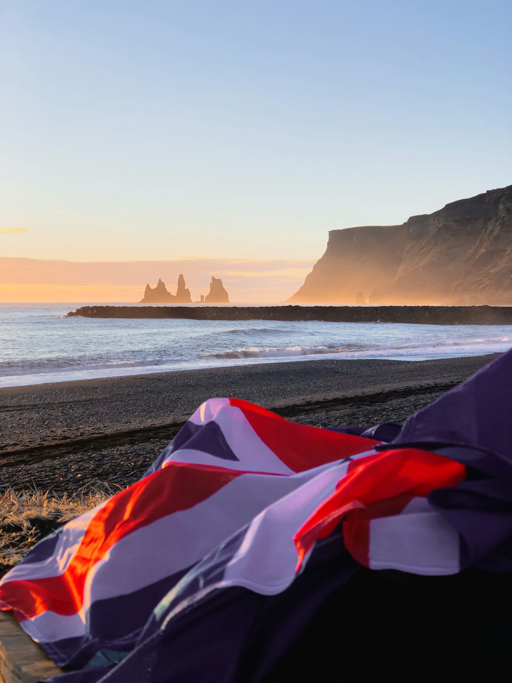 a flag laying on a beach next to the ocean