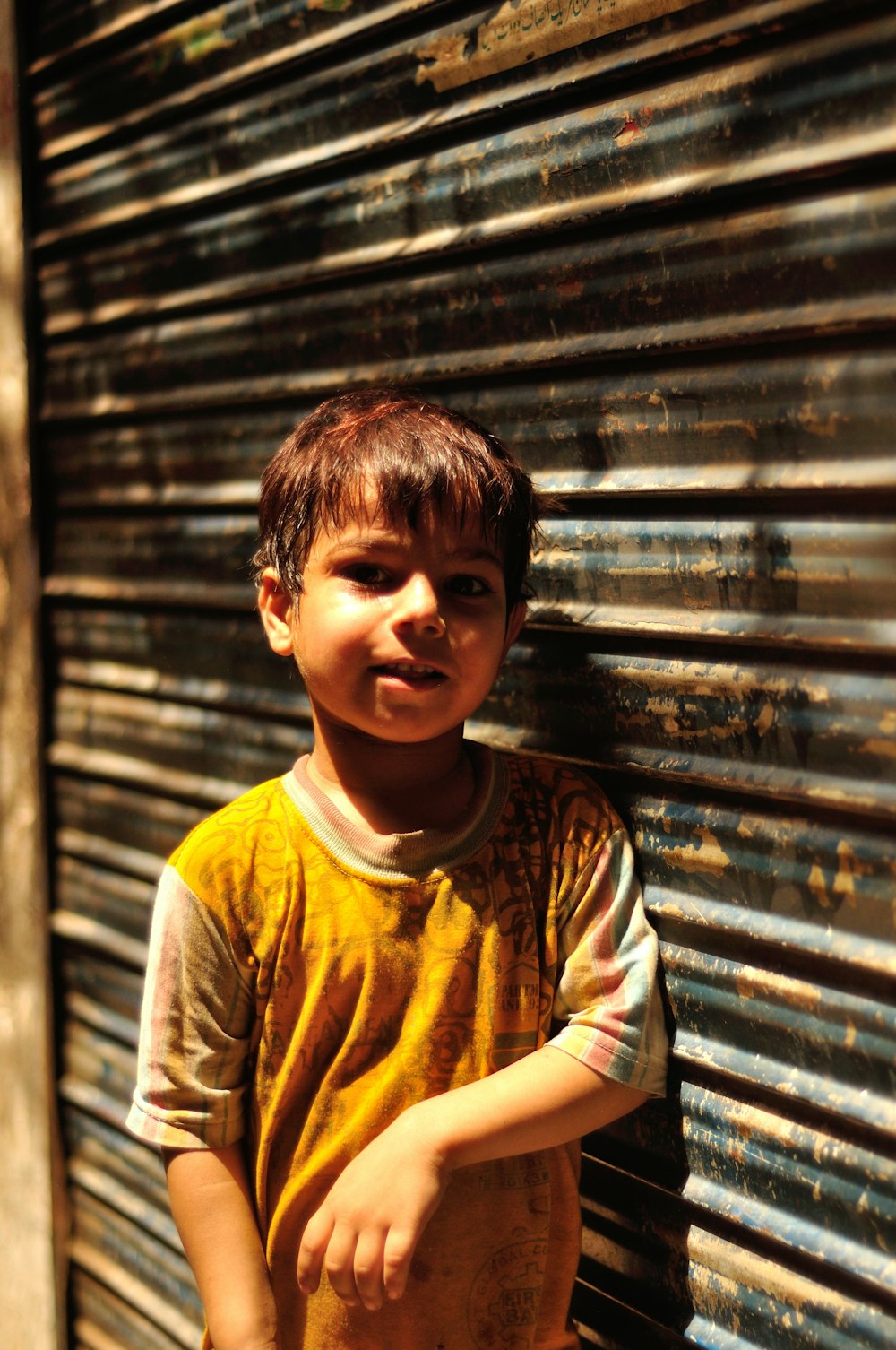 a young boy standing in front of a metal door