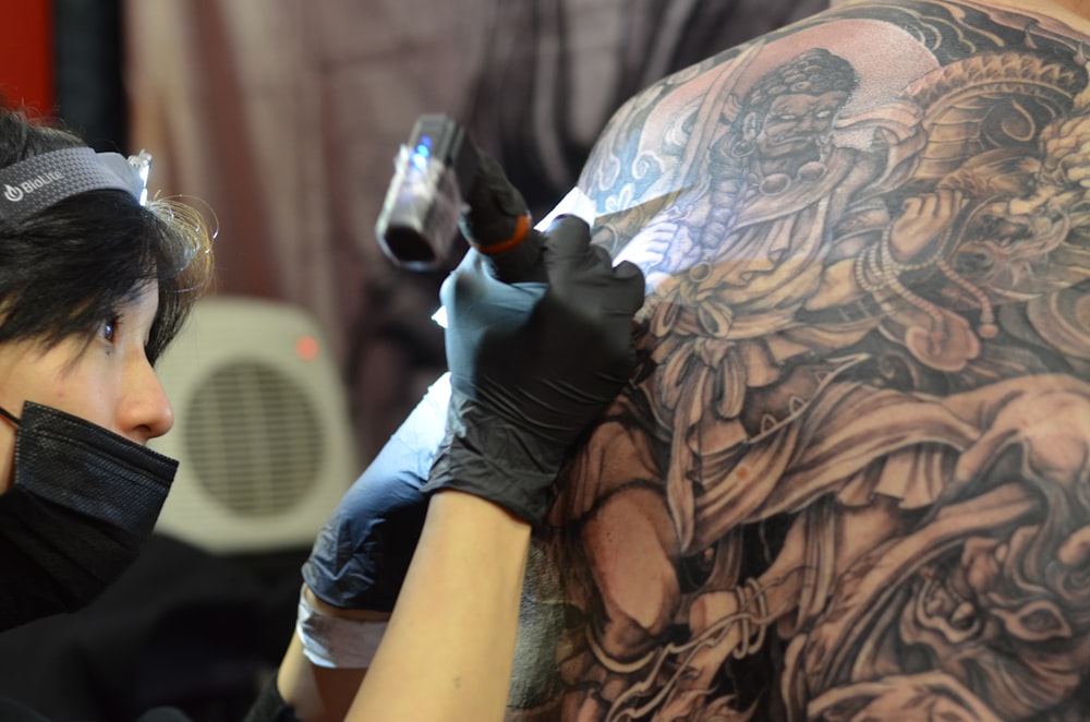 a woman getting a tattoo done on her back