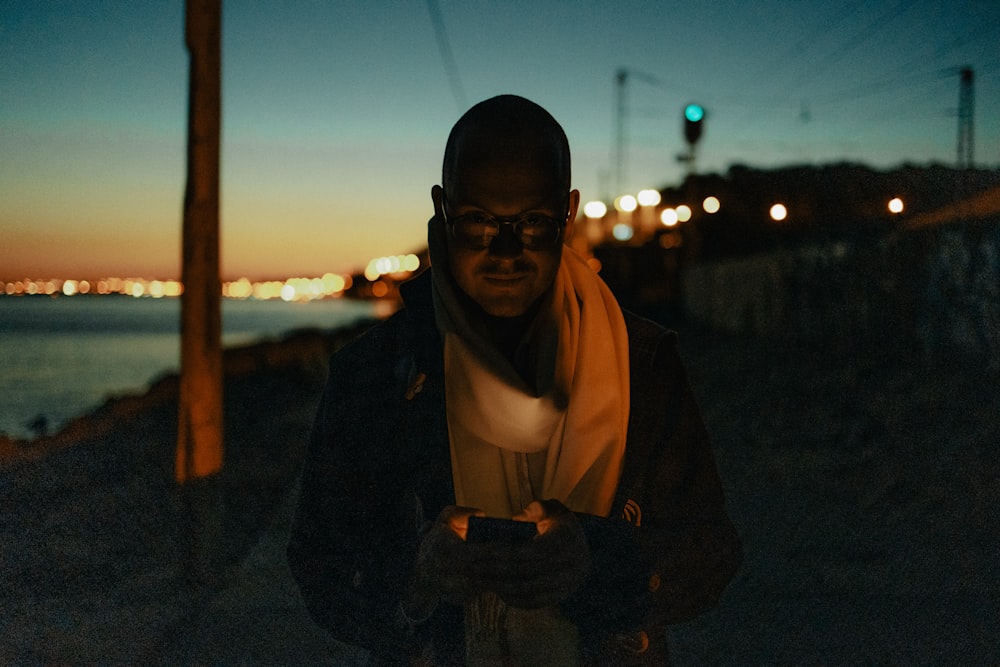 a man standing next to a body of water at night