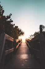 a wooden walkway leading to the beach at sunset