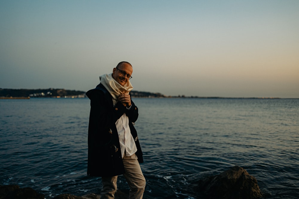 a man standing on a rock next to a body of water