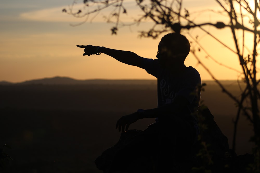 a silhouette of a person pointing a gun at the sunset