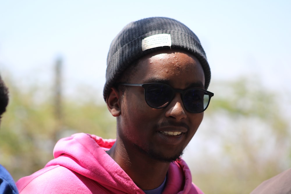 a man wearing sunglasses and a pink hoodie