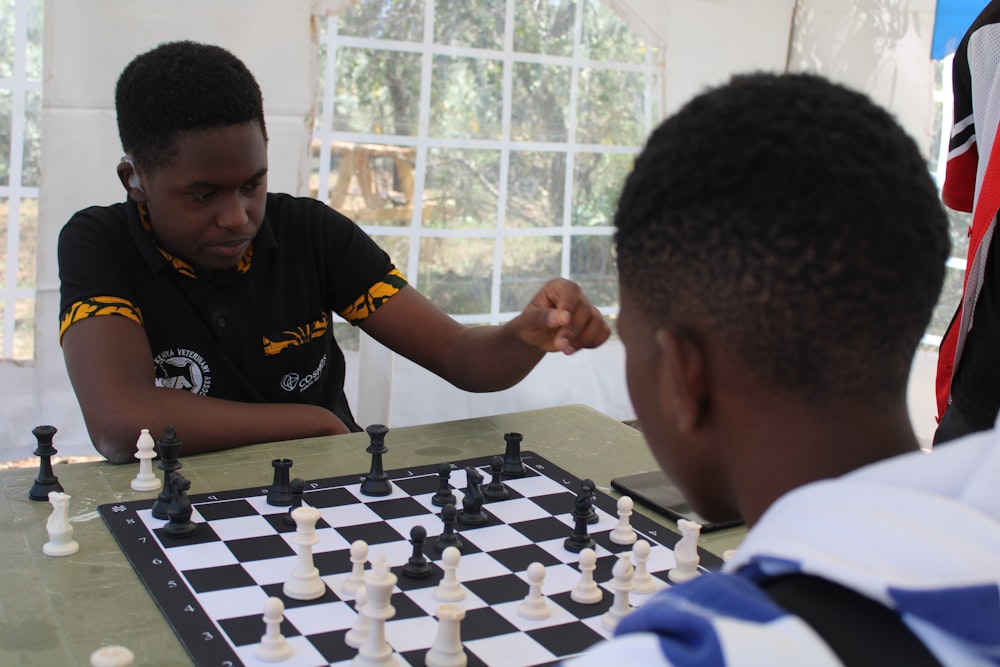 a young man playing chess with another young man