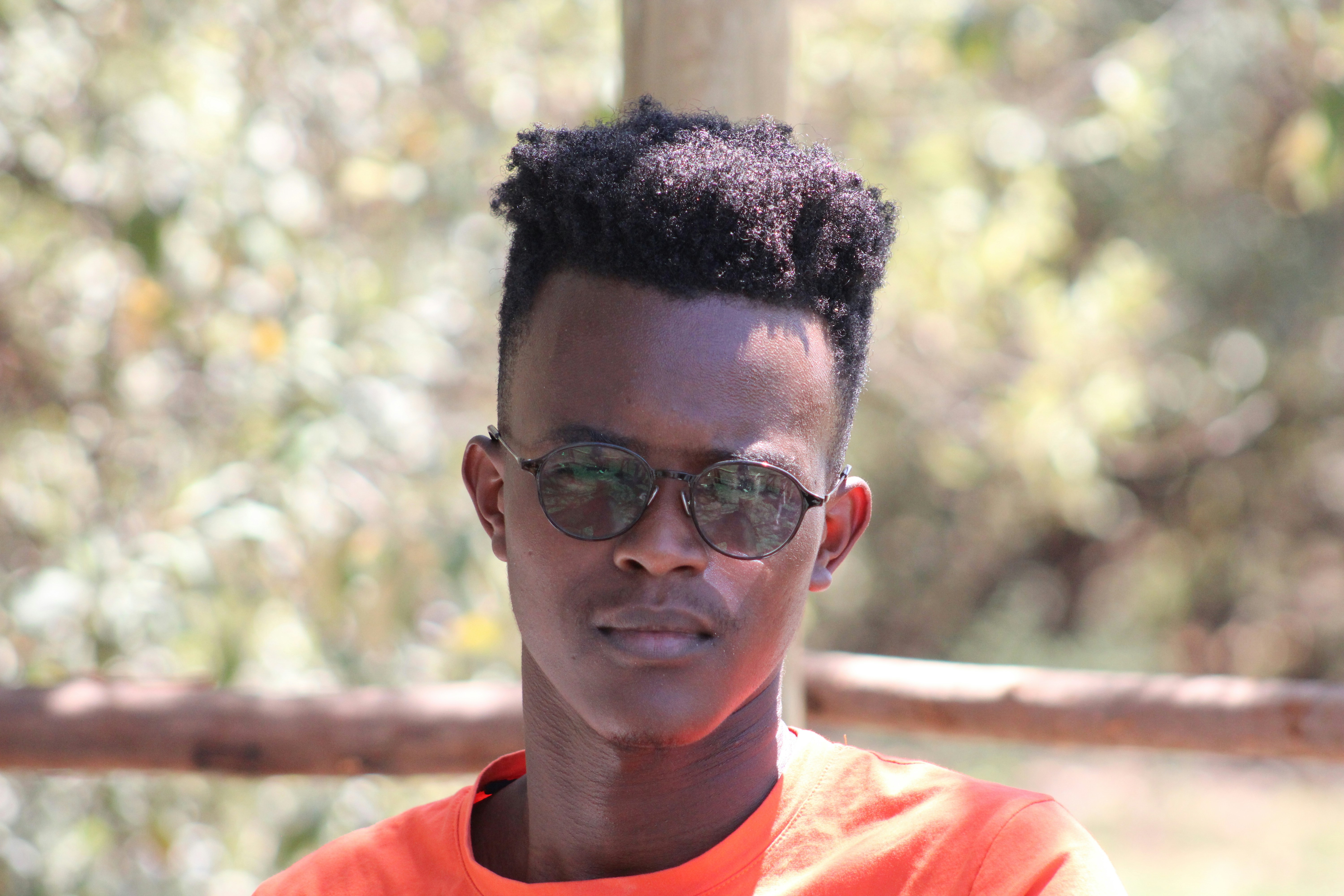 a young man wearing glasses and an orange shirt