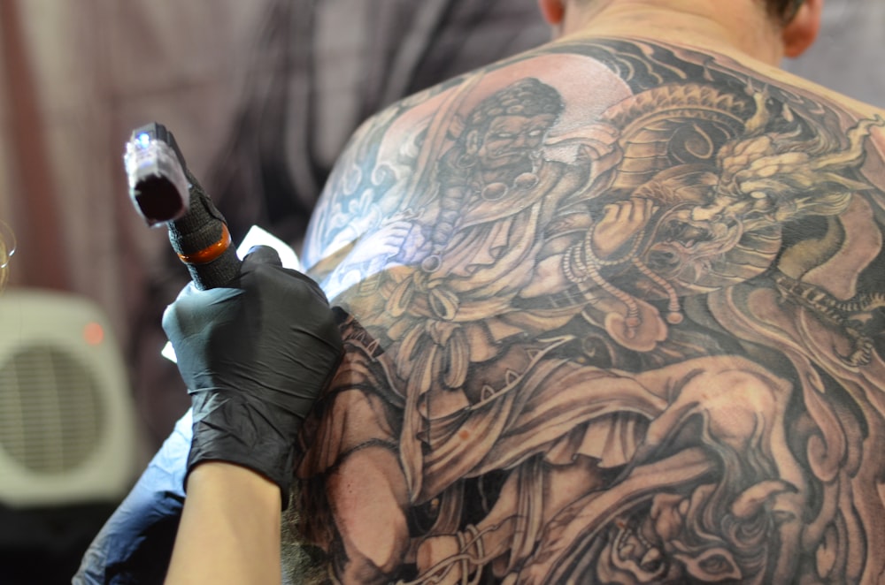 a man getting a tattoo done on his back