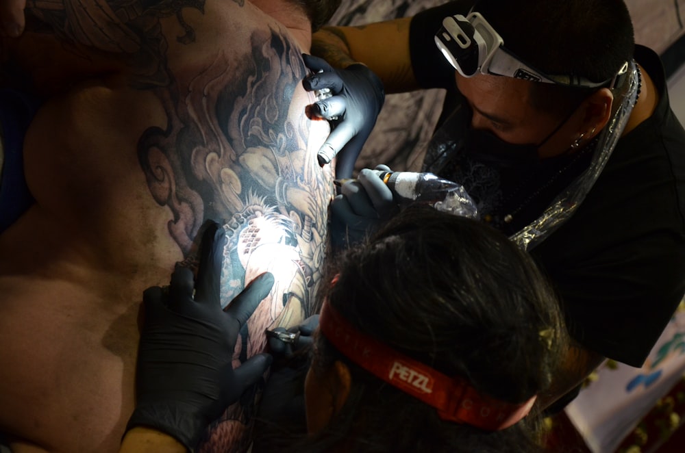 a man getting a tattoo on another man's arm