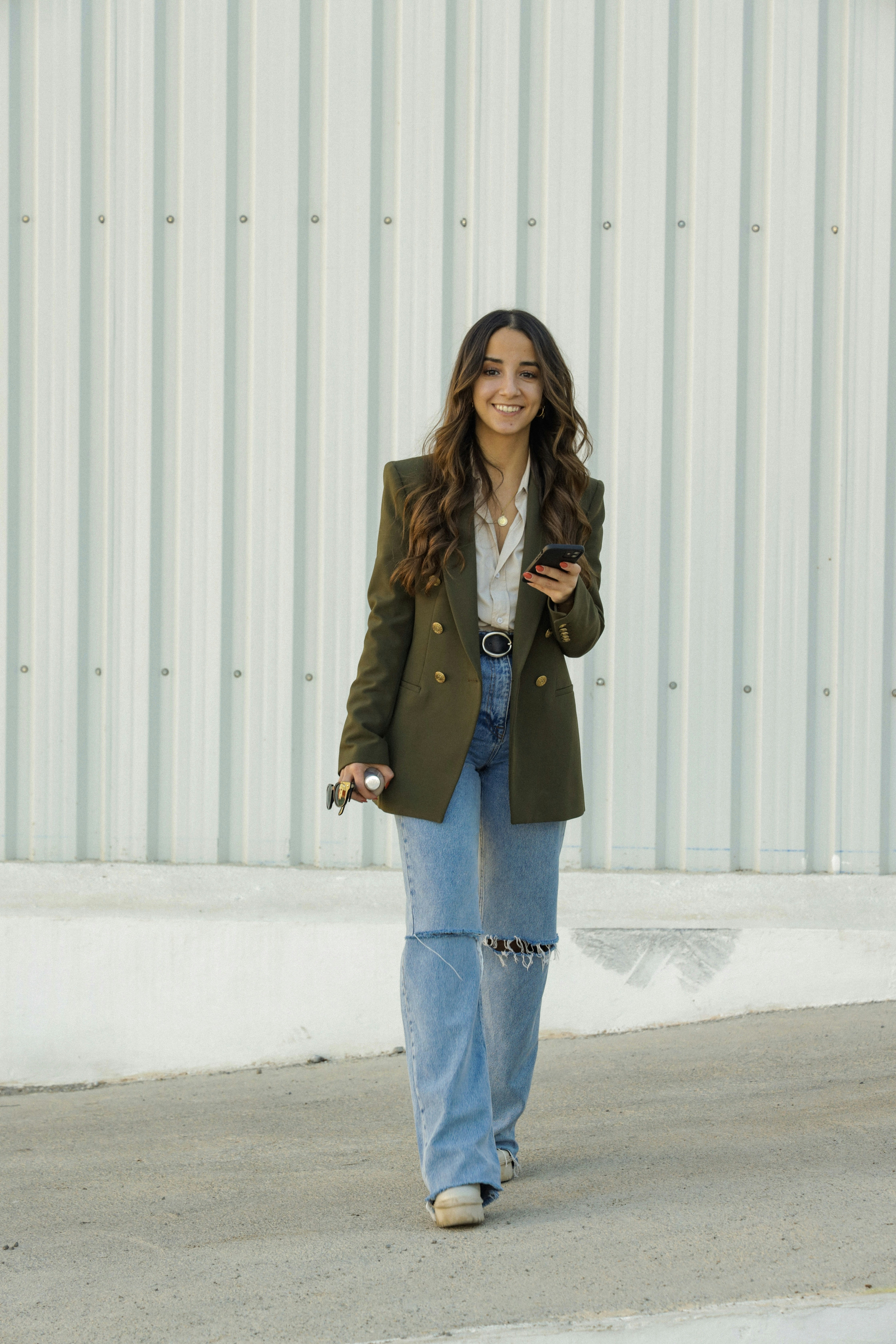a woman walking down a street while holding a cell phone