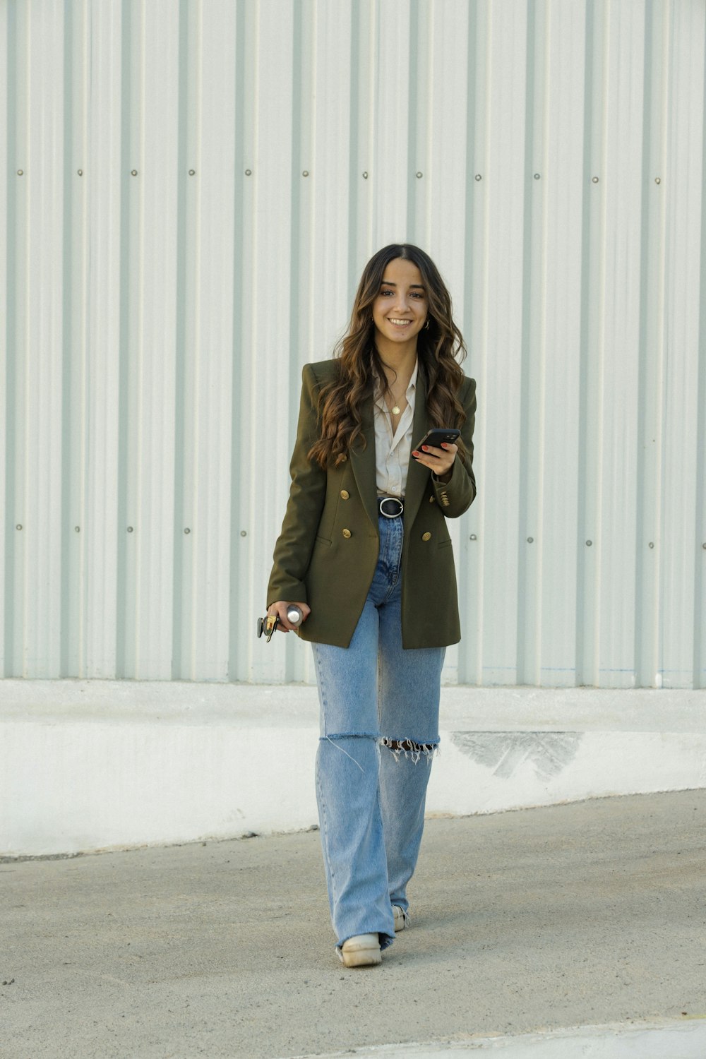 a woman walking down a street while holding a cell phone