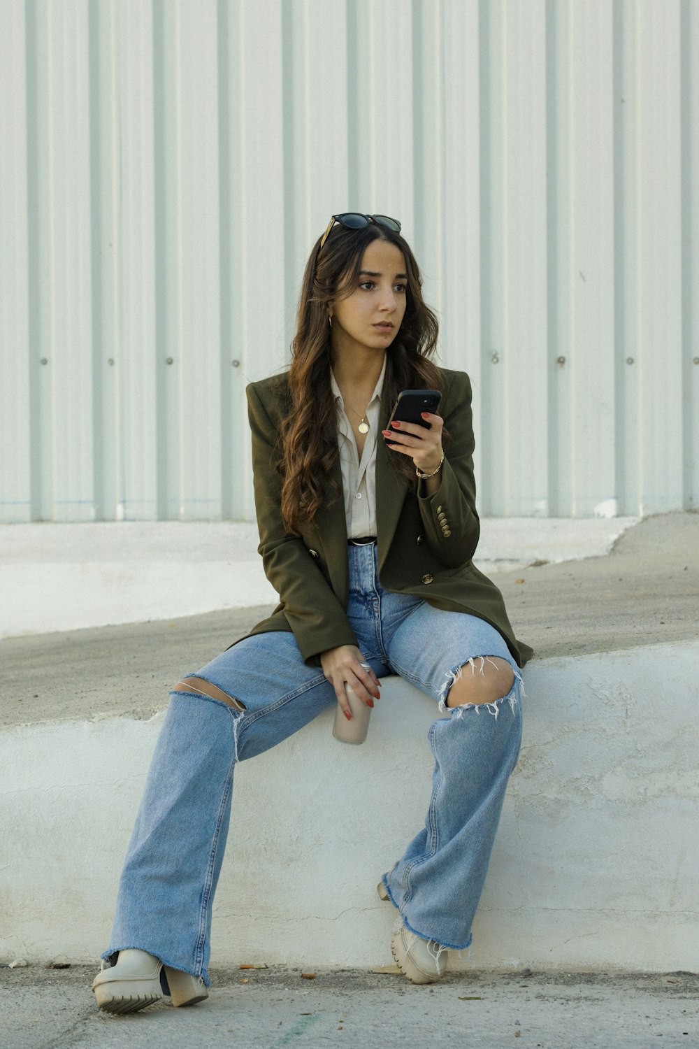 a woman sitting on a ledge looking at her cell phone