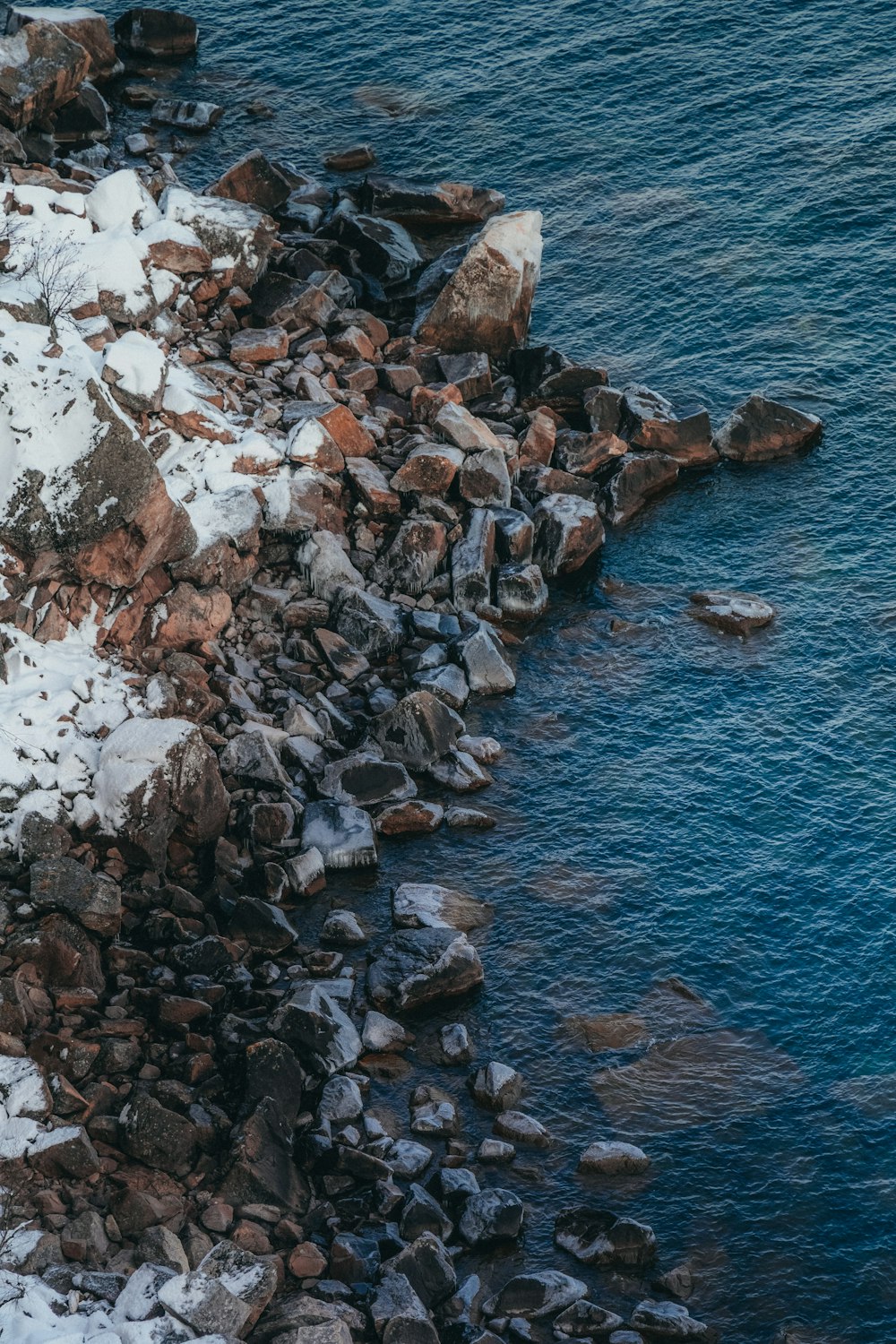 水域の隣の雪に覆われた岩だらけの海岸