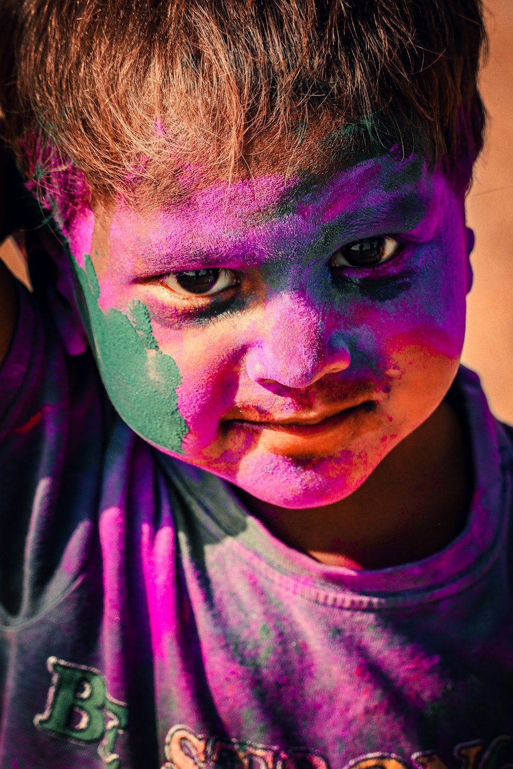 a young boy is covered in purple and green paint