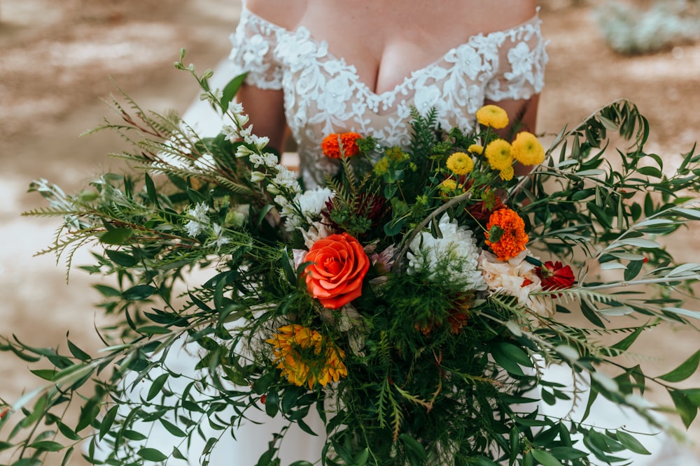 Une femme en robe de mariée tenant un bouquet de fleurs