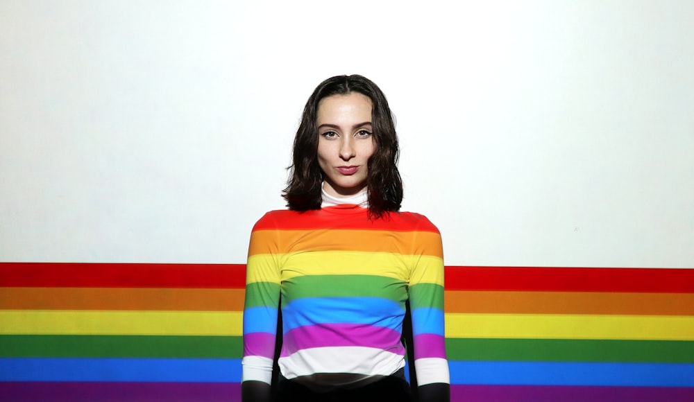 uma mulher em pé na frente de uma parede colorida do arco-íris