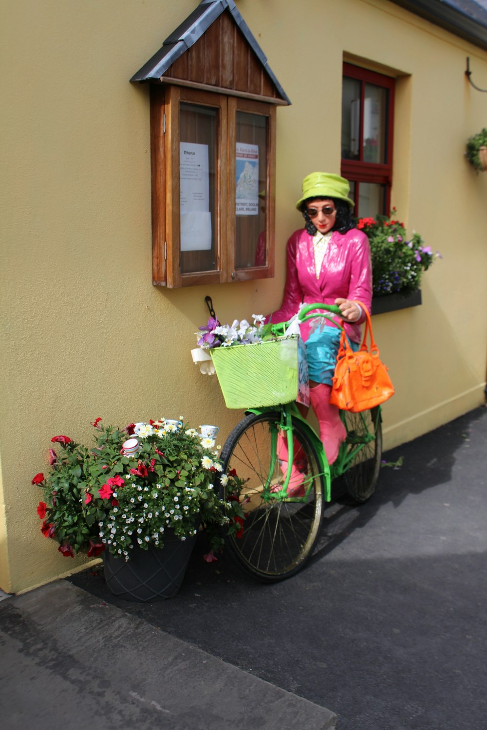 バスケットに花を入れた自転車の隣に立っている女性