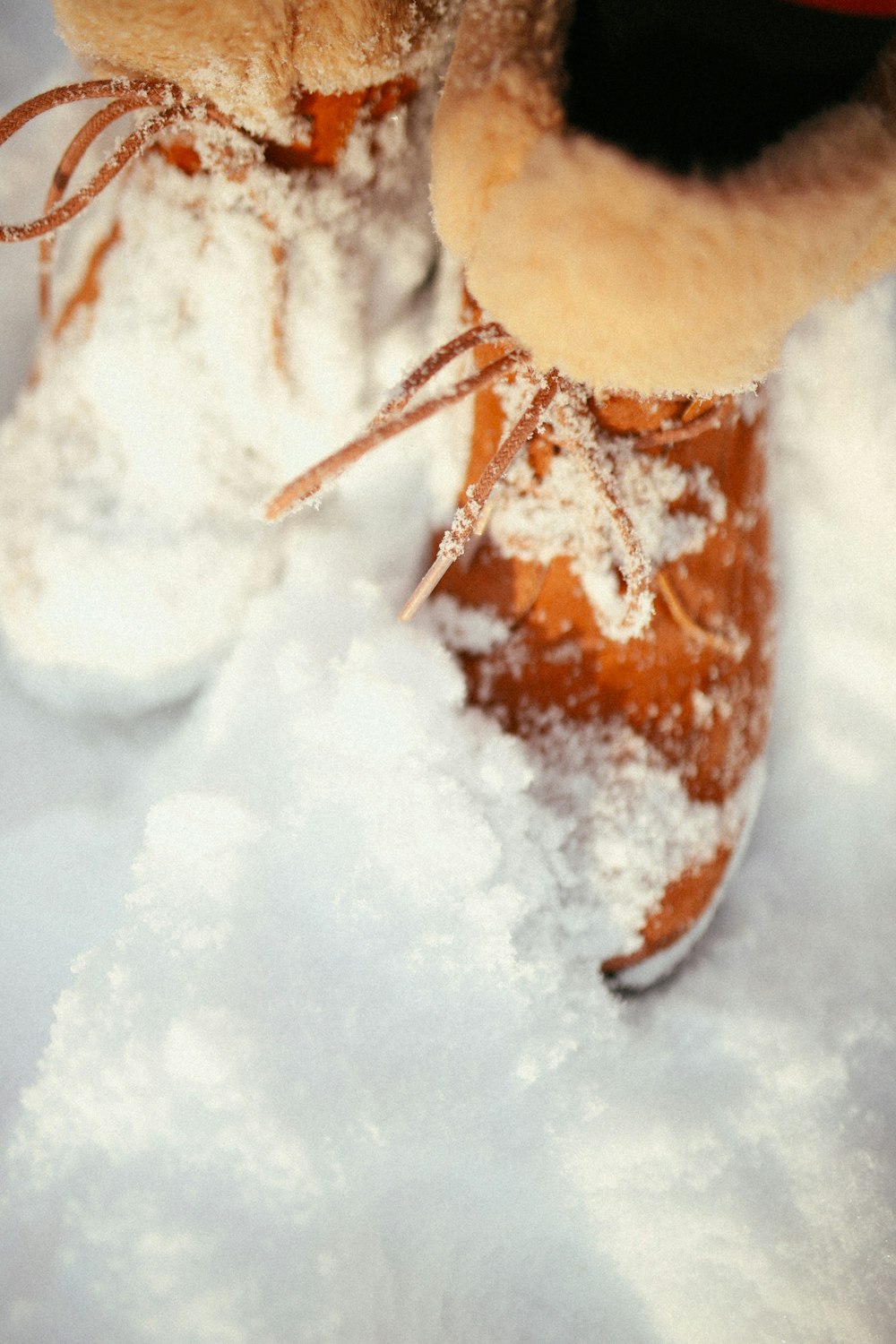 a teddy bear sitting on top of a pair of snow boots