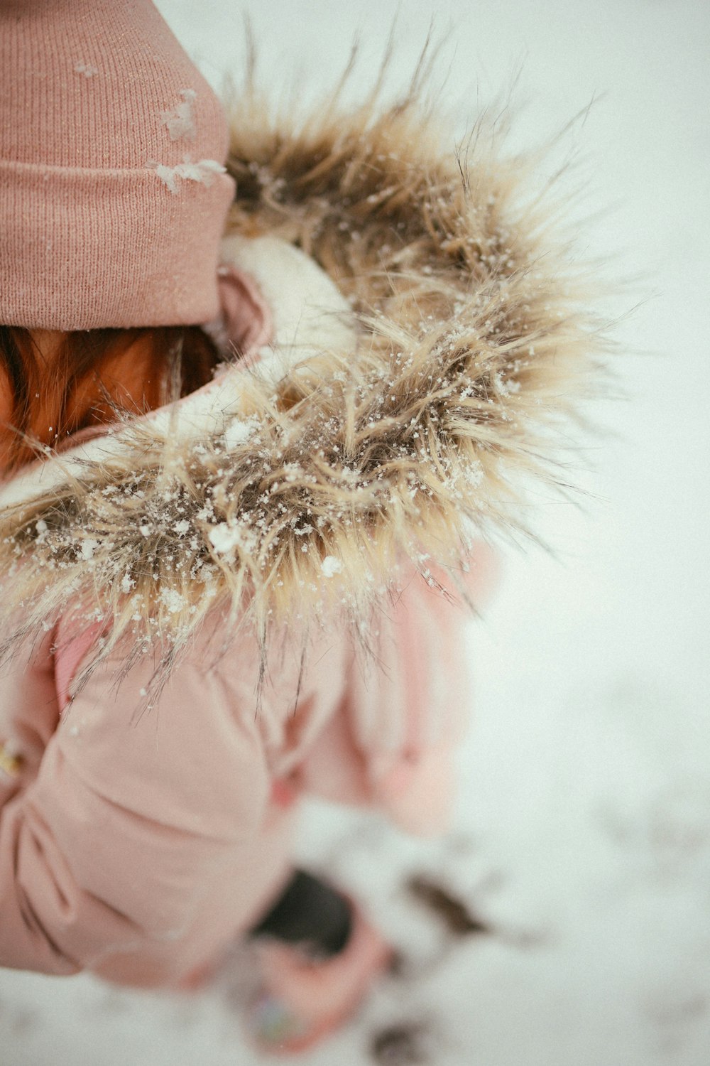 a little girl wearing a pink coat and a pink hat