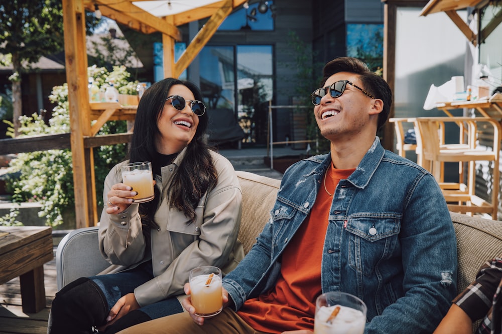 a man and a woman sitting on a couch drinking beer