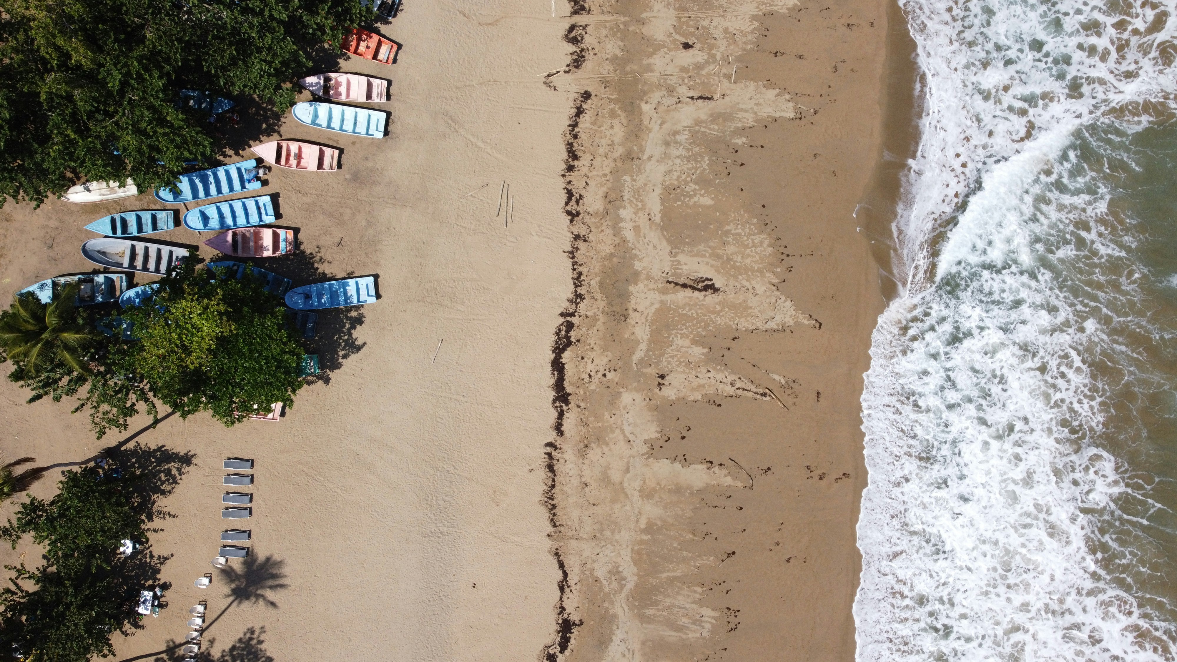 an aerial view of a beach with several boats