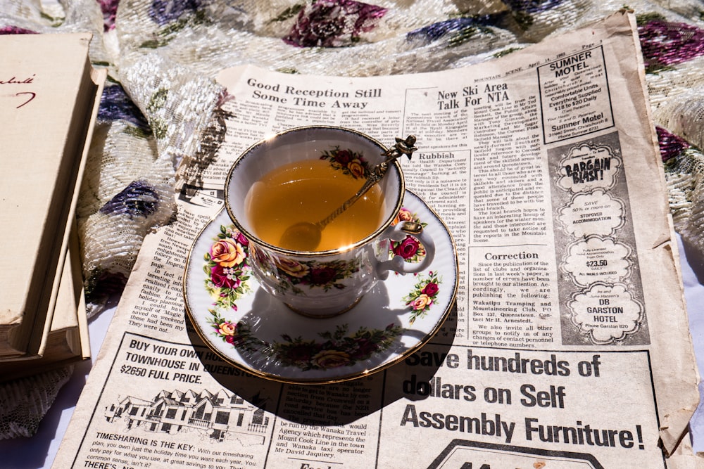 a cup of tea sitting on top of a newspaper