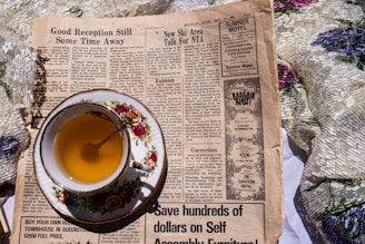 a cup of tea sitting on top of a newspaper