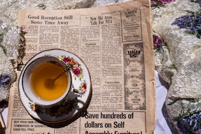 a cup of tea sitting on top of a newspaper