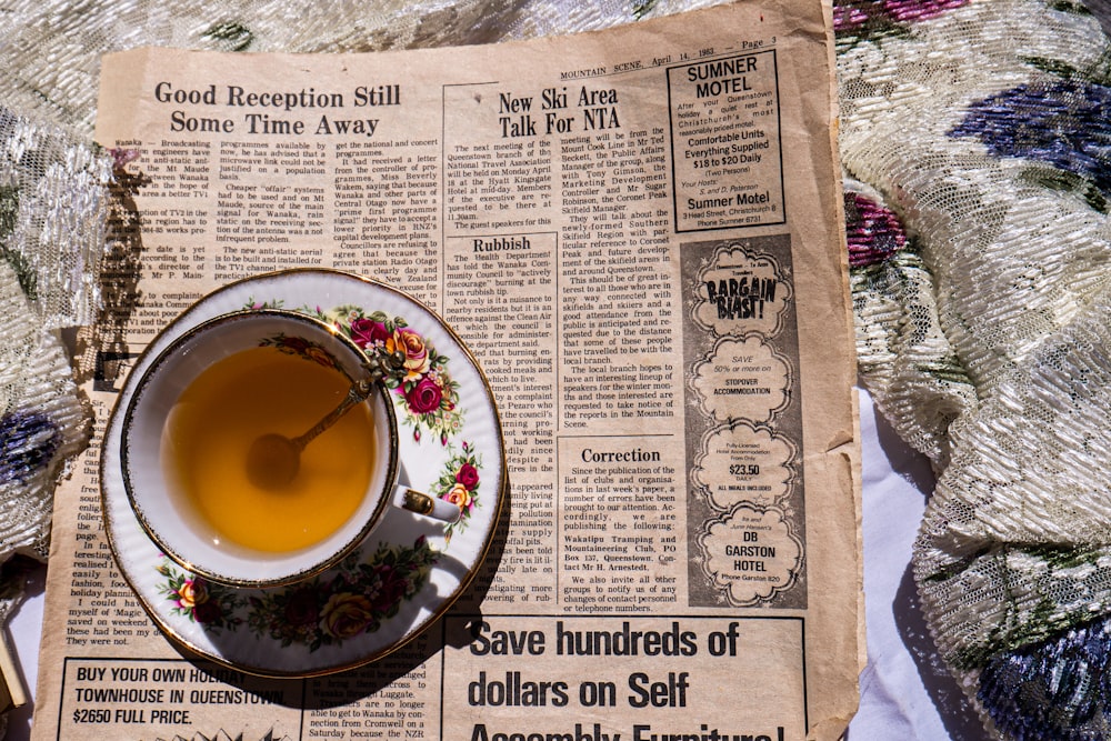 a cup of tea sitting on top of a newspaper