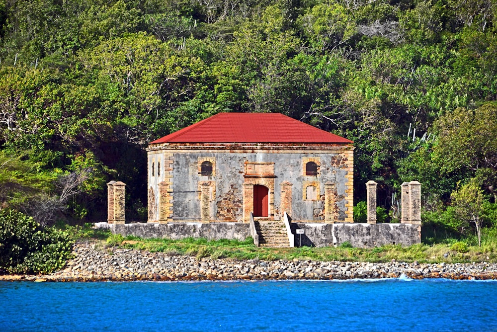 an old stone building with a red roof next to a body of water