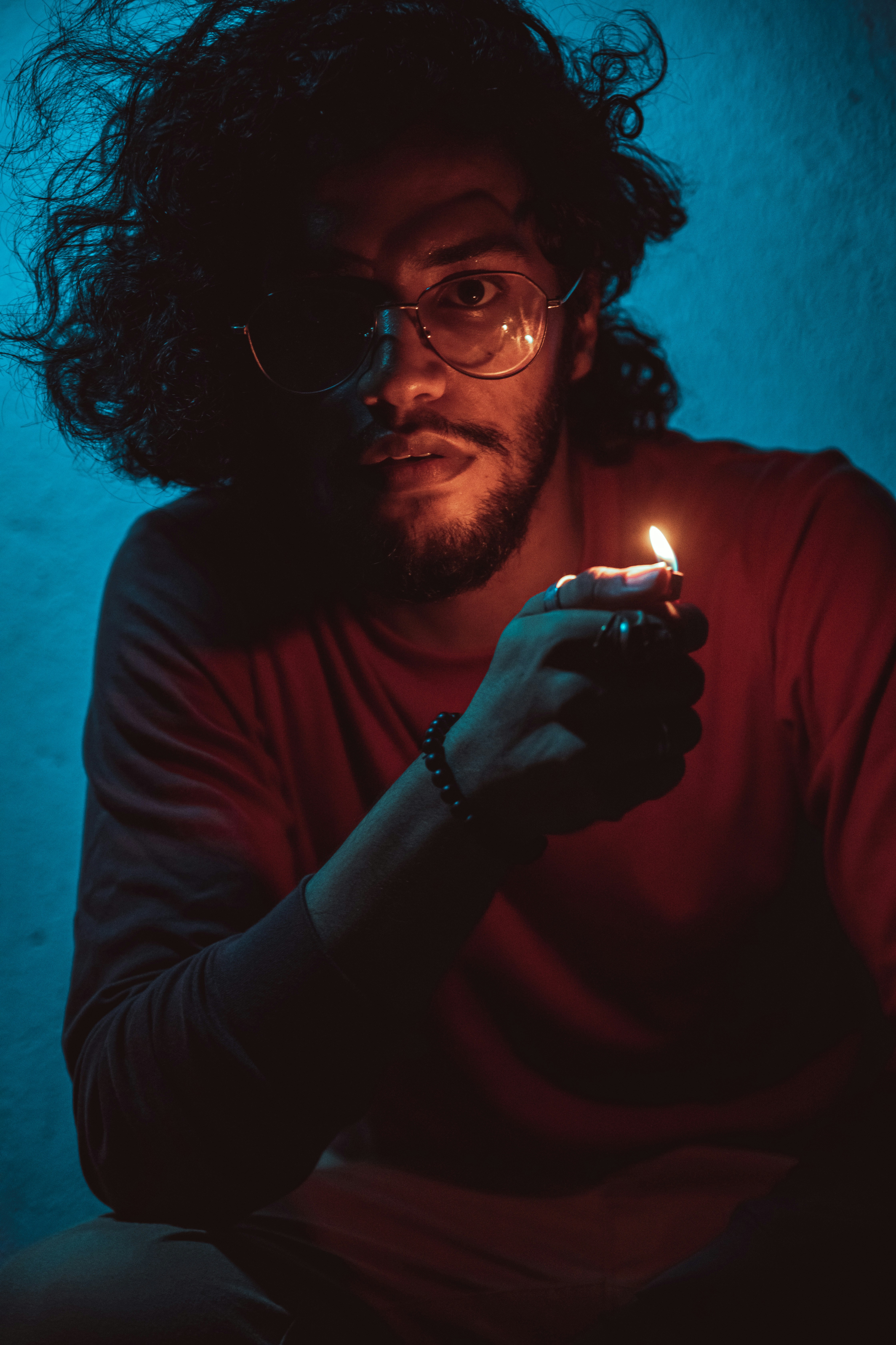a man with glasses holding a lit cigarette