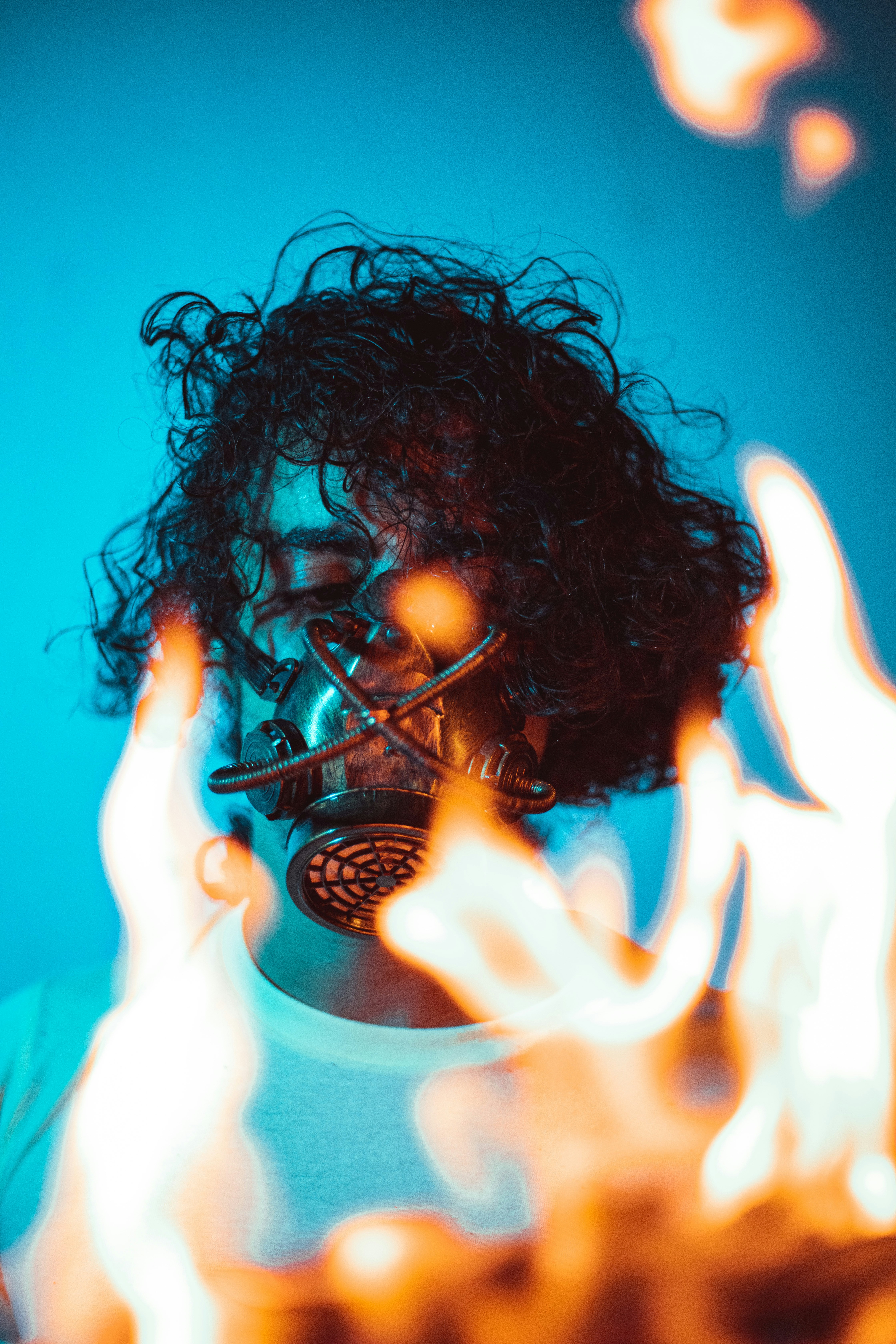 a woman wearing a gas mask with flames in front of her