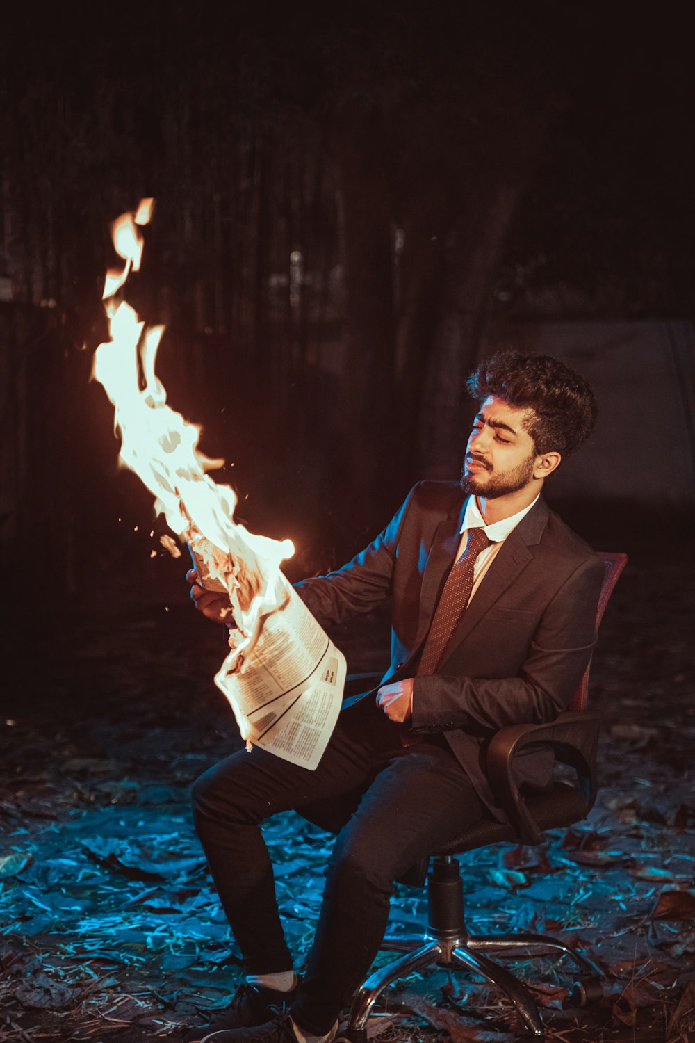 a man in a suit sitting on a chair holding a newspaper