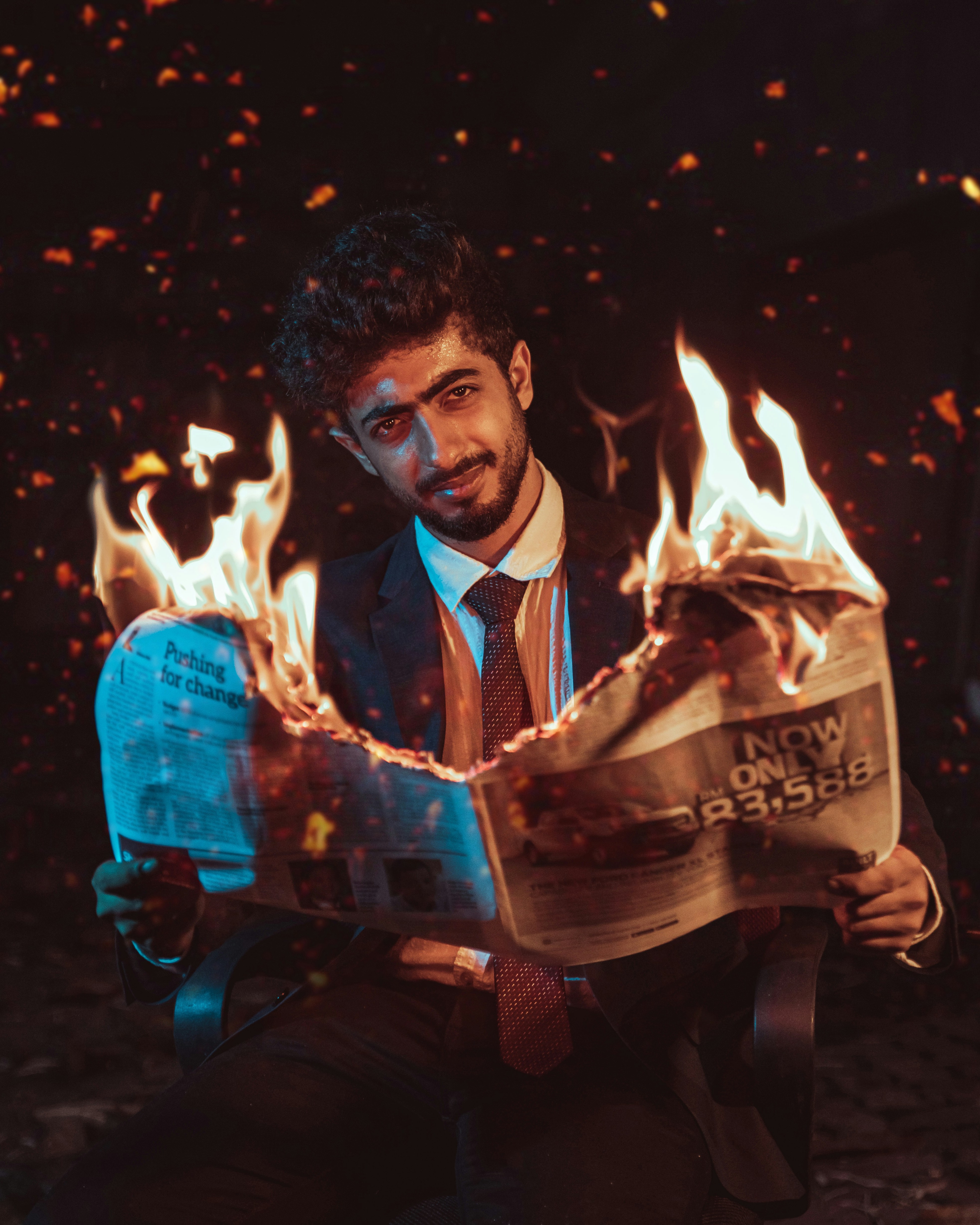 a man in a suit and tie holding a newspaper with flames coming out of it